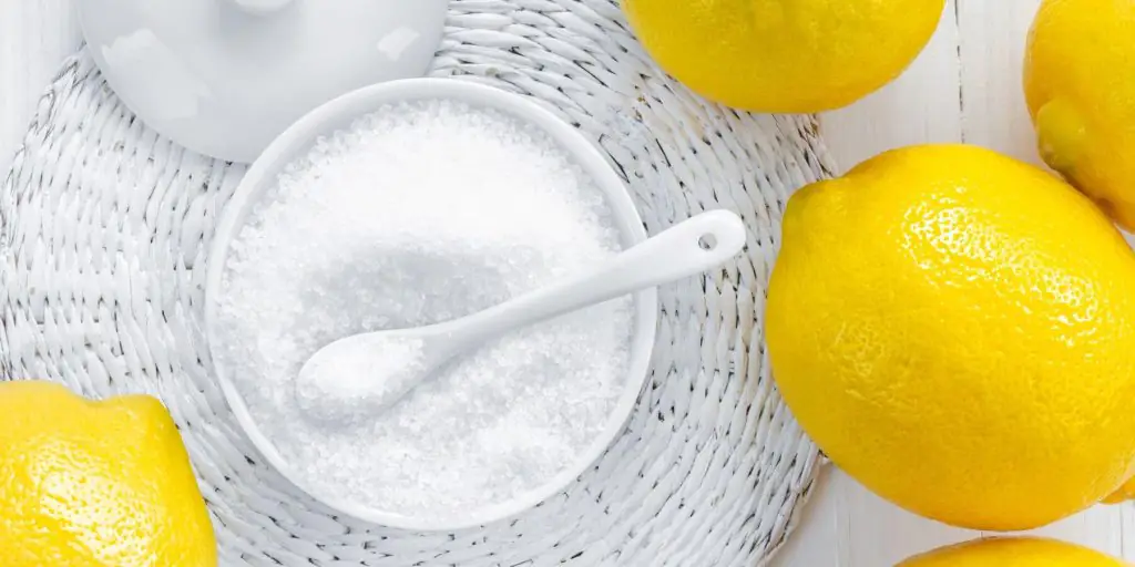 Citric acid granules in a bowl with lemons