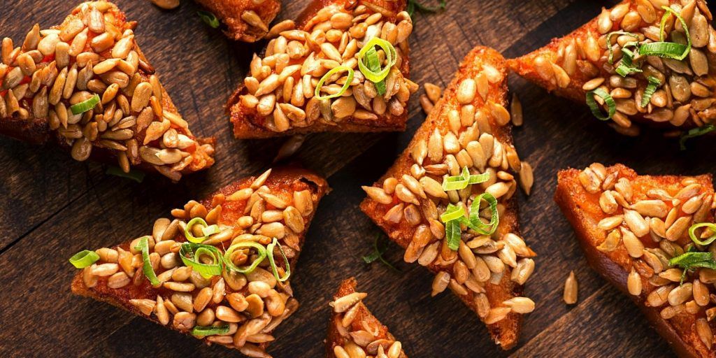 Crispy shrimp toast topped with toasted sunflower seeds