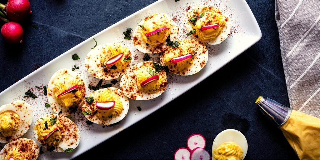 Top view of deviled eggs with radish and paprika