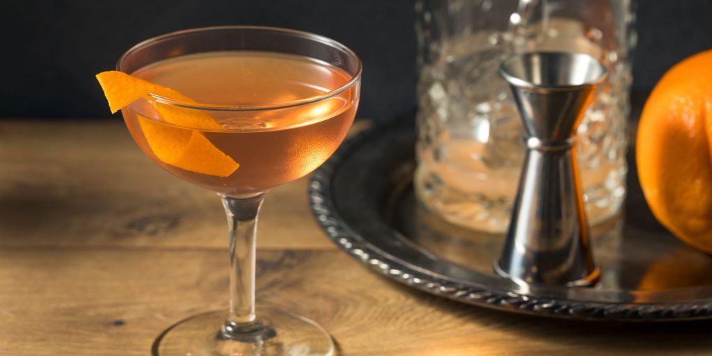 El Presidente Cocktail against a dark background featuring a fresh orange twist