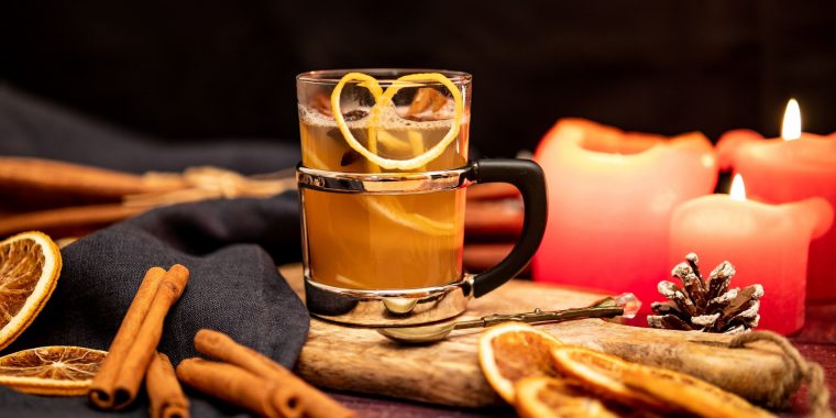 A mug of Apple Cider Hot Toddy on a wooden tray surrounded by fall decoration elements