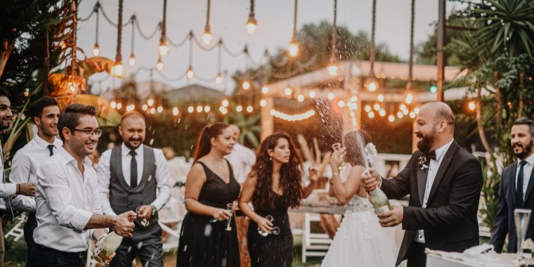 Groom popping a bottle of Champagne at wedding reception