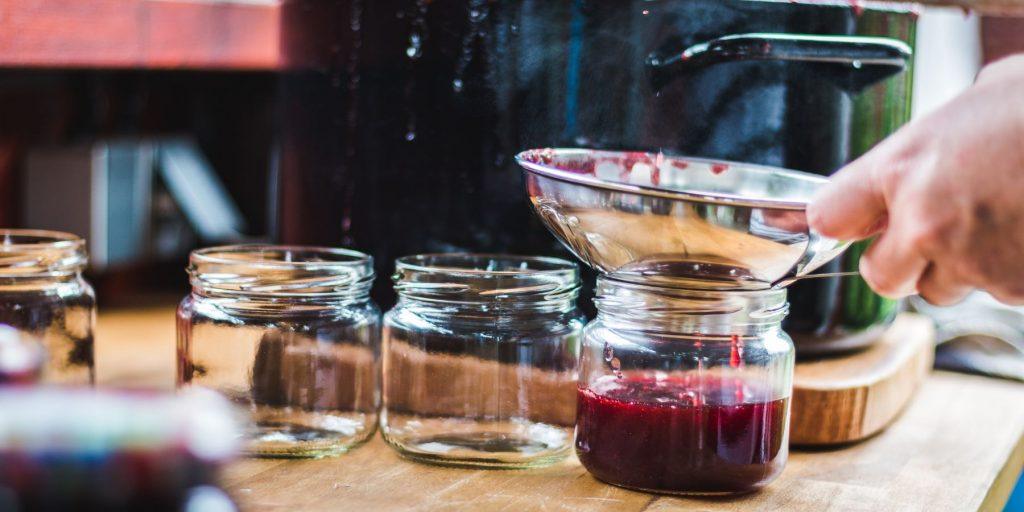 Strawberry syrup for cocktails being strained into jars