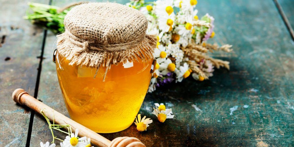 A jar of honey syrup with a honey dipper