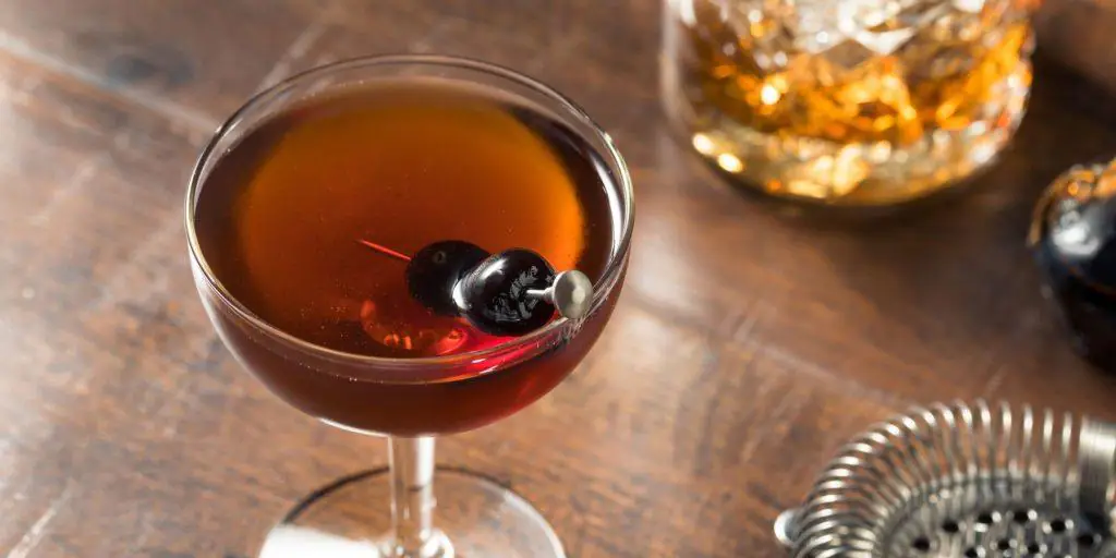 A very grownup Sake Manhattan cocktail garnished with Luxardo cherries