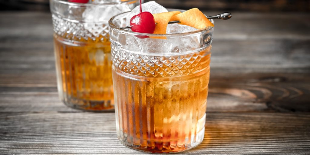Two Scotch Old Fashioned cocktails garnished with orange and cherry