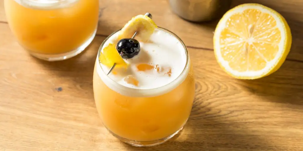 Two Scotch Sour cocktails garnished with lemon and cherry