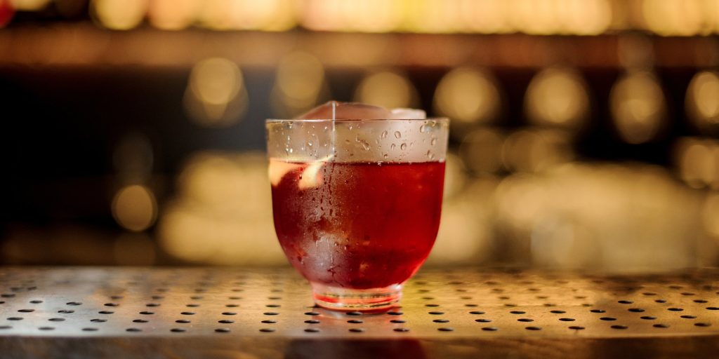 A Vieux Carre cocktail on a bar counter garnished with a lemon twist