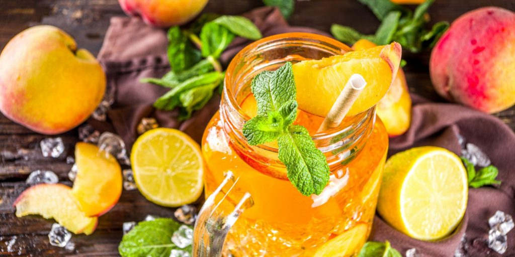A fruity Iced Tea Sangria cocktail garmished with mint and surrounded by fresh fruit slices
