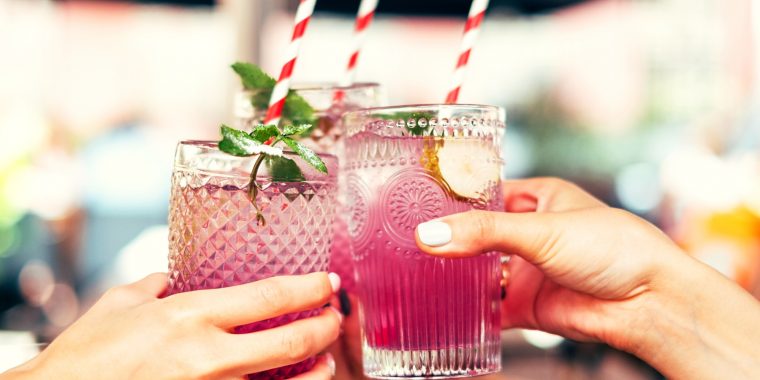 Hands clinking together pink spring cocktails