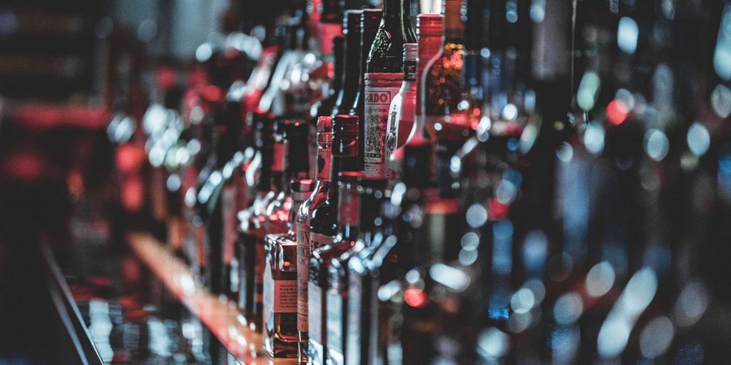 A side view of a bar shelf full of liquor bottles in a slightly moody setting