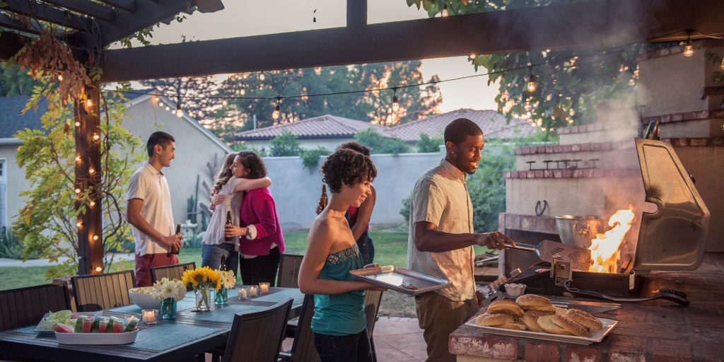 Friends gathered around a BBQ in a bright outdoor space at home for a Memorial Day BBQ