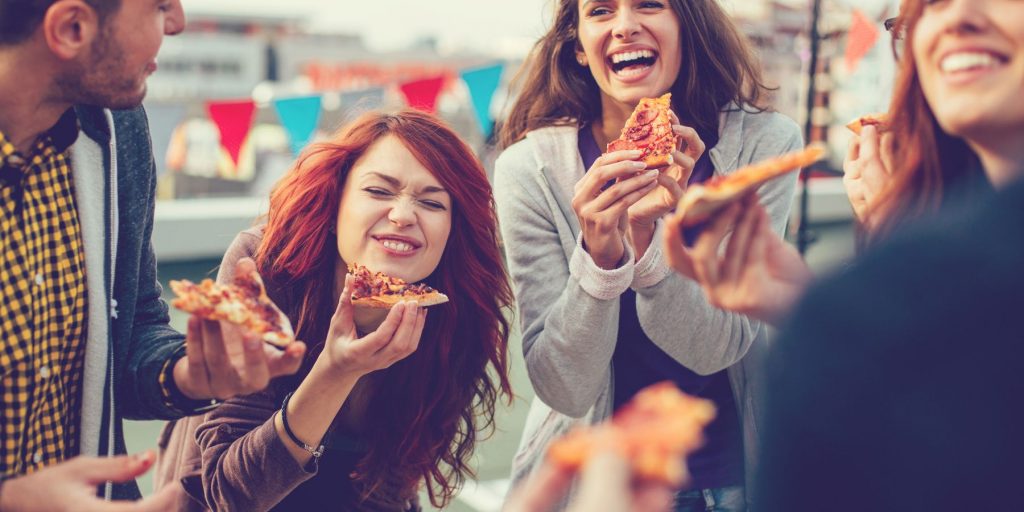 Tight shot of a group of friends enjoying pizza at a Memorial Day party at home