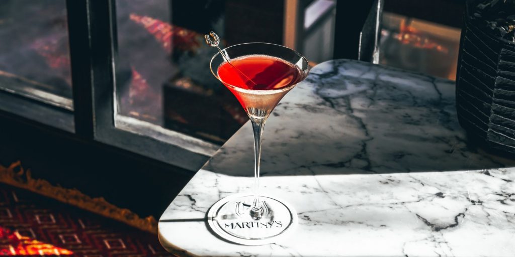Close up of a lovely red cocktail in a Martini glass in a splash of sunlight on a marble table in the Martiny's cocktail bar in NYC
