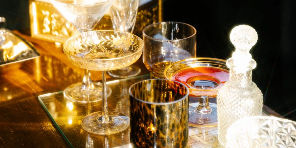 Close up of a collection of fancy vintage cocktail glasses and decanters on a Bohemian bar cart