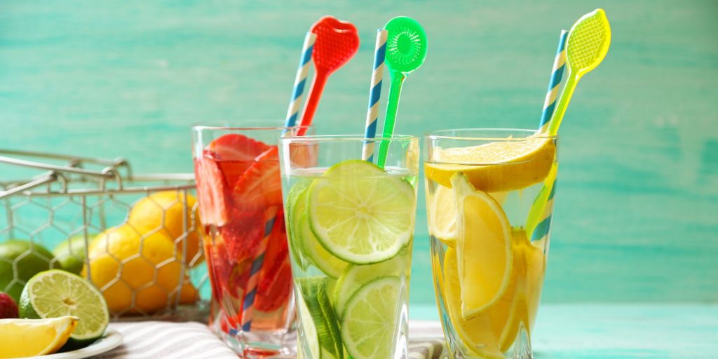 Close up of three summery drinks with cocktail stirrers in bright colors on a DIY bar cart