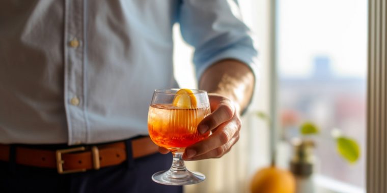 Close up of a man in a button-down shirt holding a Father's Day cocktail in a bright and inviting kitchen