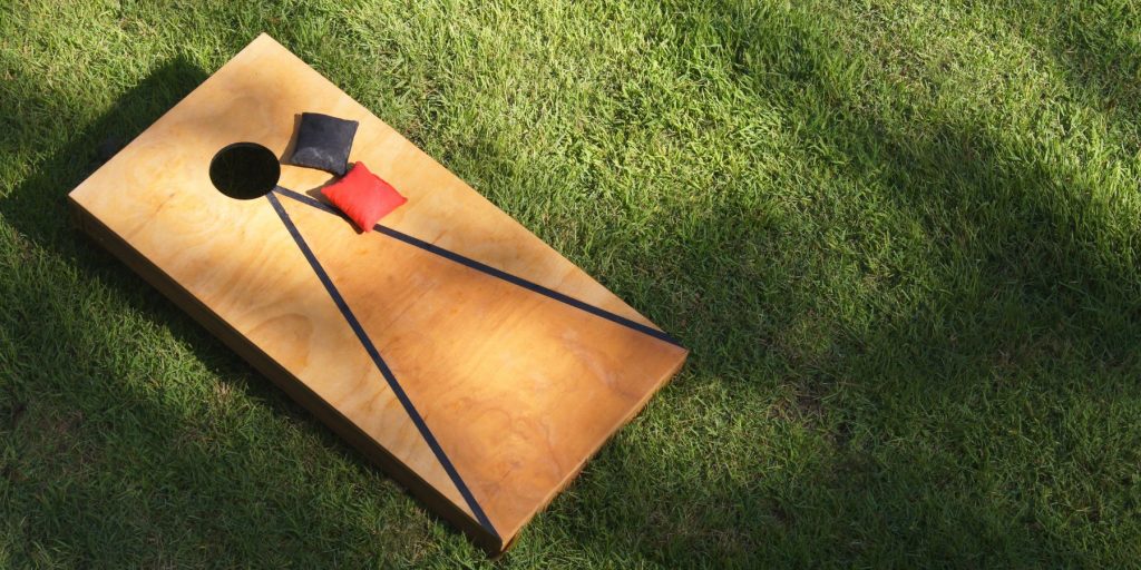 Close up of a game of cornhole set up on a grassy patch at a tailgate party