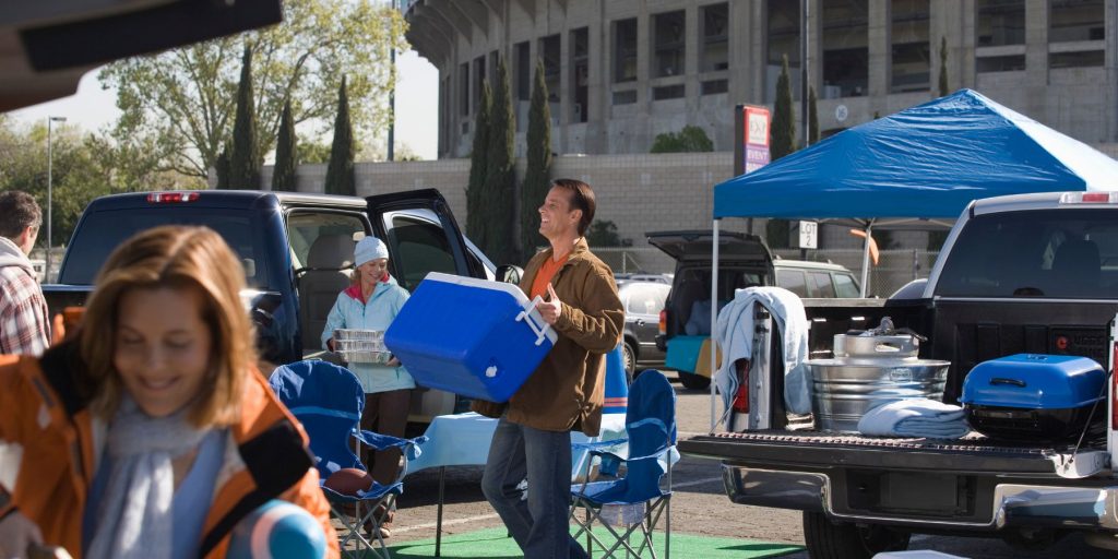 A group of friends setting up for a tailgating party in the parking lot of a sport venue