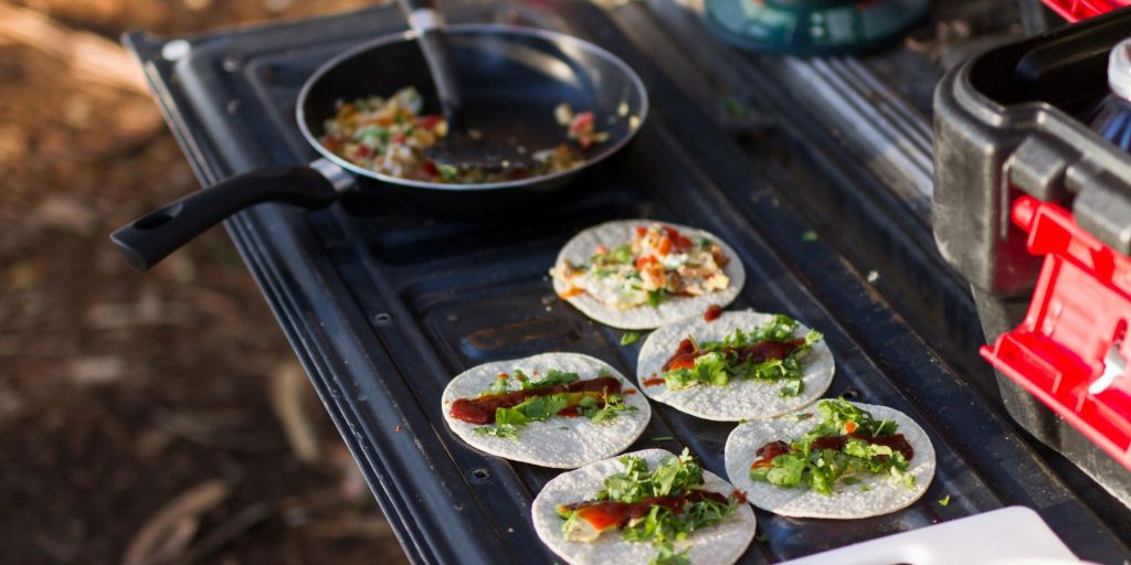 Close-up of tacos being prepared on the tailgate of a truck