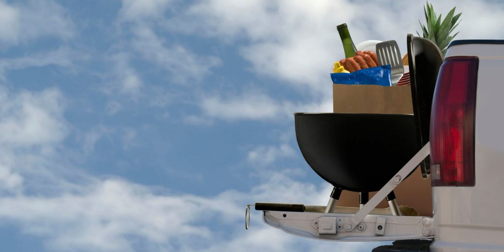 Close-up of a BBQ set-up on the tailgate of a truck against a blue sky