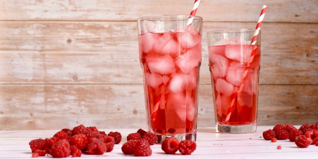 Close up front view of two Raspberry Lime Rickey cocktails against a rustic wooden backdrop