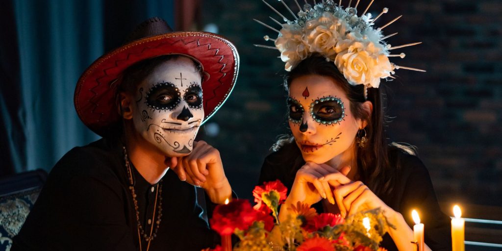 A close-up of a man and a woman dressed up in costume for a Day of the Dead celebration