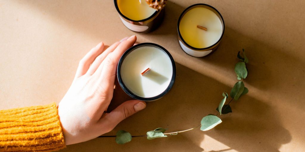 Top view of a woman's hand arranging sustainable candles on a Thanksgiving gift table