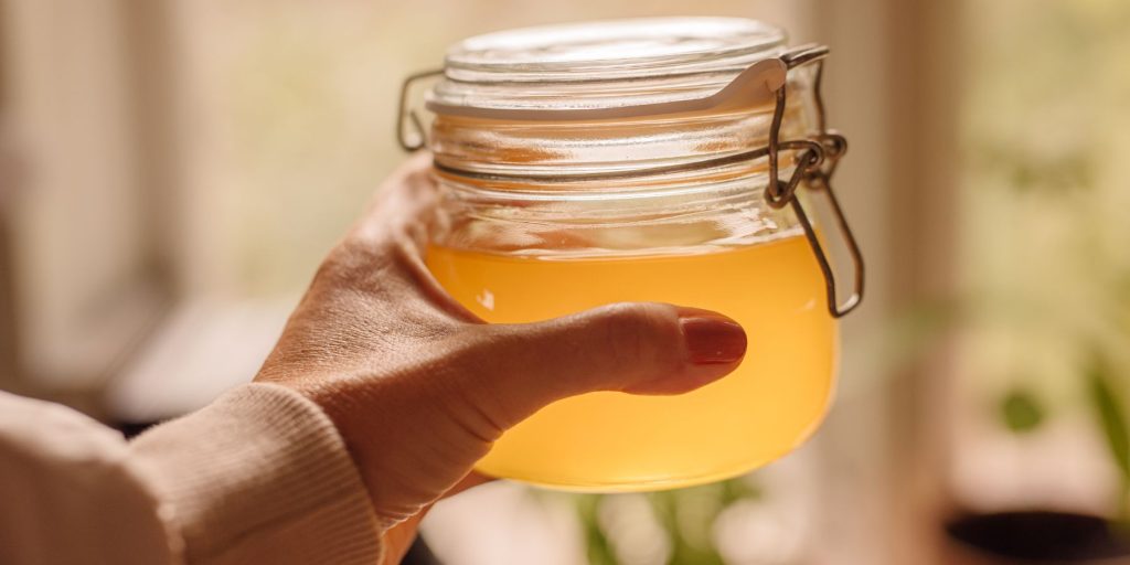 Close up of a woman's hand holding a jar of clarified cocktail mixture