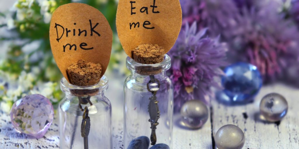 Close up of two glass bottles with keys and 'Eat Me', 'Drink Me' cards that form a part of a Mad Hatter's Tea Party game for adults