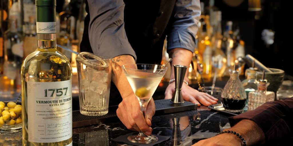 A bartender serving a Classic Martini with olive garnish