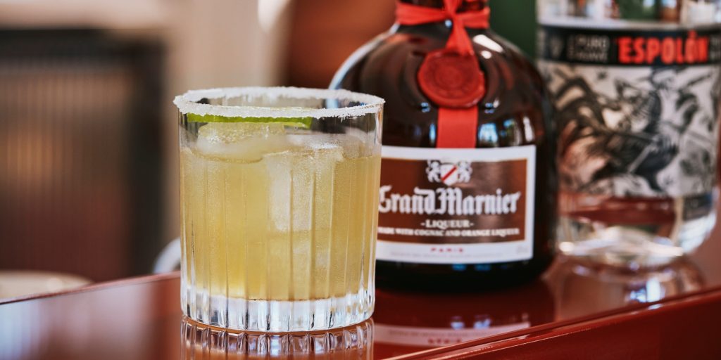 Grand Margarita served on a bar counter next to a bottle of Grand Marnier and Espolòn Tequila