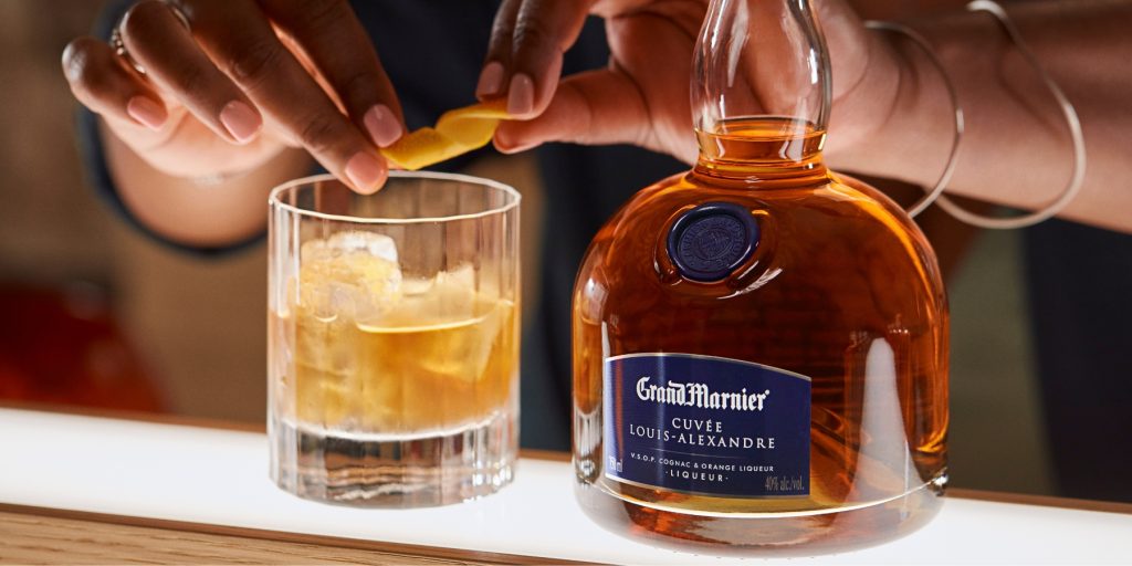 A bartender creating an orange peel twist for a Grand Old Fashioned cocktail