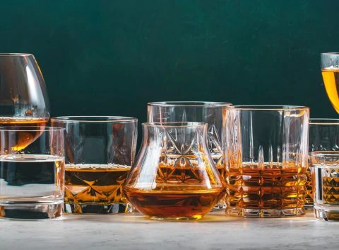 Wide variety of brandy glasses with golden and amber liquids, arranged on a marble table, photo by 5ph/Adobe Stock