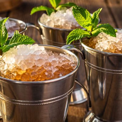 Three stainless steel tumblers of Mint Juleps with crushed ice and mint sprigs