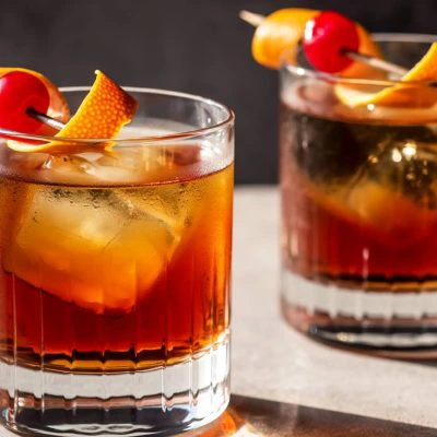Two glasses of Old Fashioned cocktails with ice and garnish