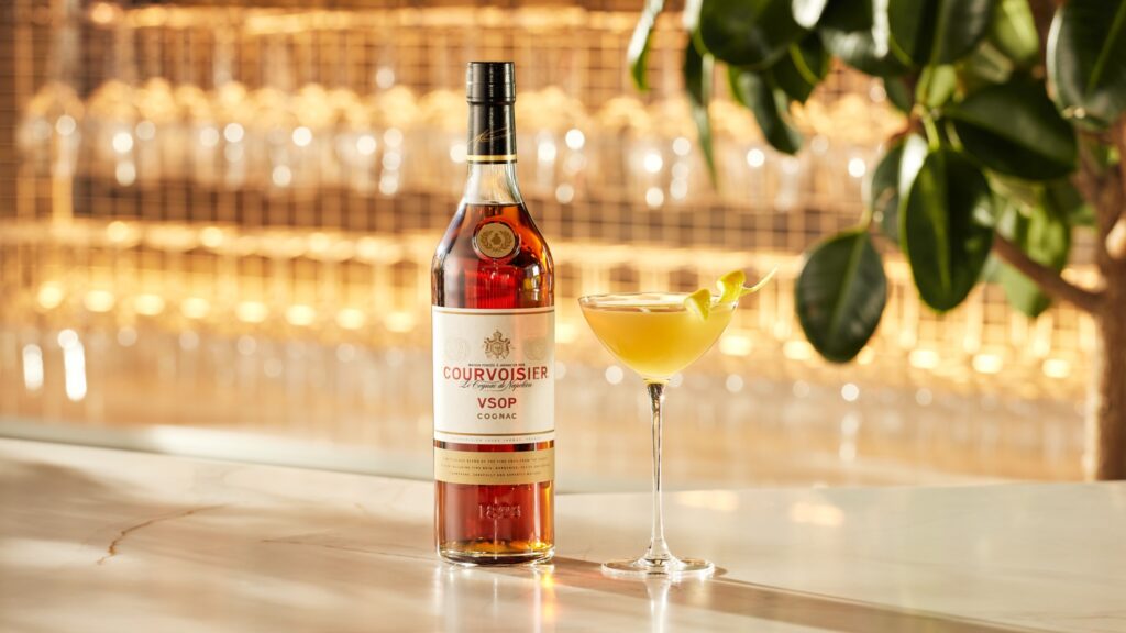 Bottle of Courvoisier VSOP and a sidecar cocktail on a shiny surface